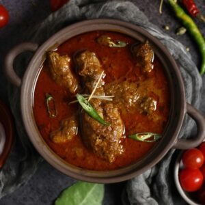 Aromatic Indian curry with meat and spices served in a traditional clay pot, garnished with chili.