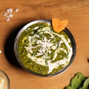 Top view of traditional Indian Palak Paneer garnished with cream and vegetables.