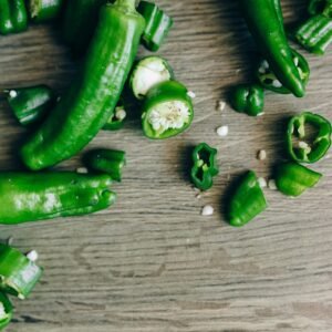 Sliced green chillies scattered on a wooden table, highlighting freshness and spice.