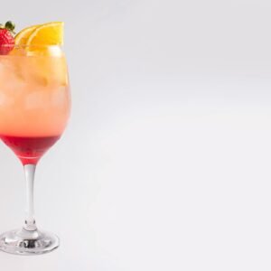 Refreshing cocktail with strawberry and orange garnish in elegant glass, perfect for summer.