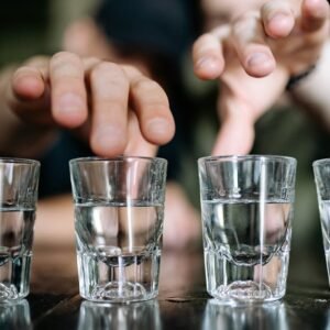 Hands reaching for shot glasses on a wooden table, close-up view emphasizing the moment.